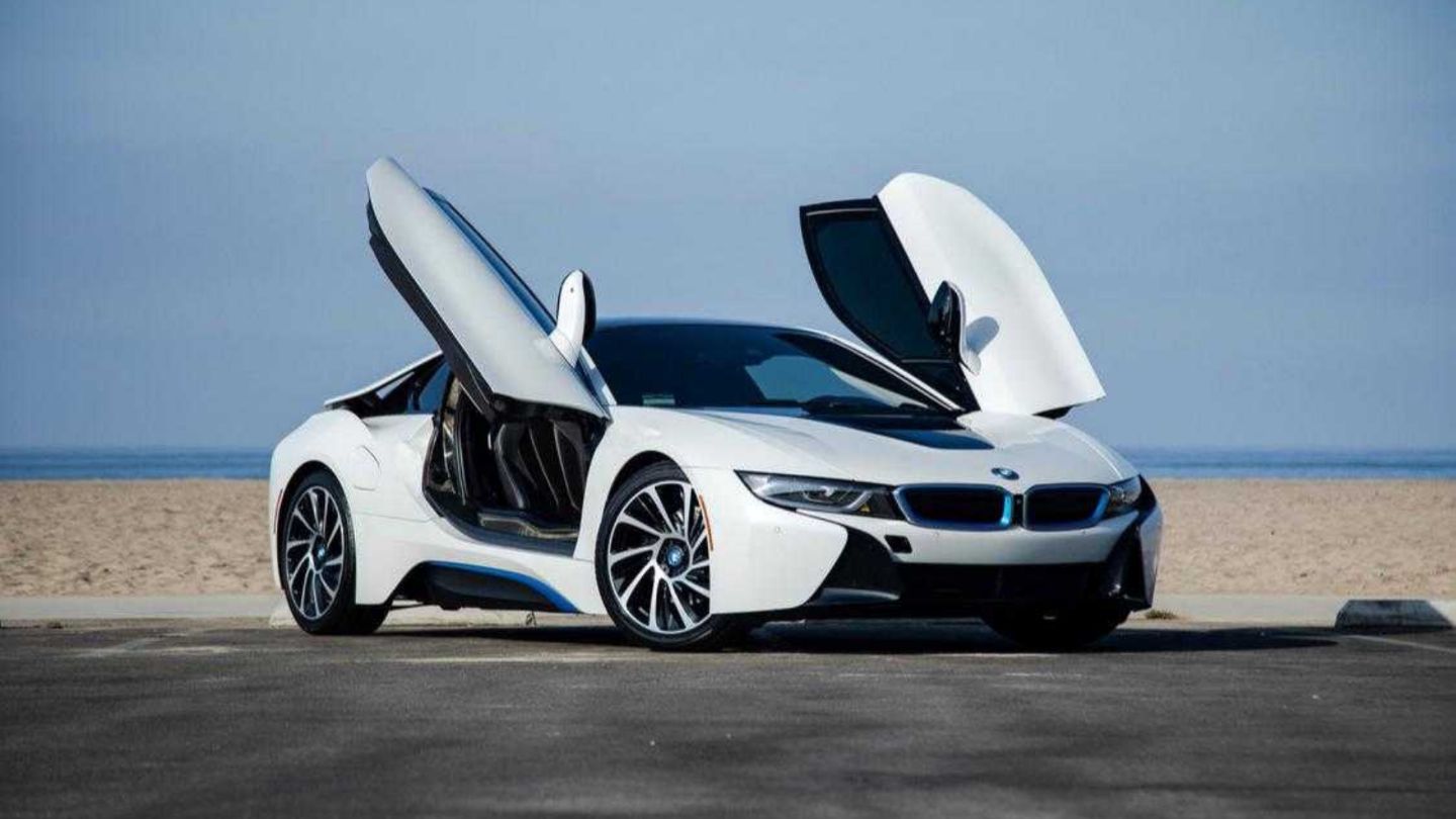 White BMW i8 with butterfly doors open on beach